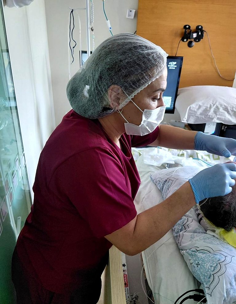 Julia Alcantara realizando exame de EEG junto ao paciente